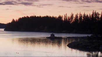Movie still from “Your Sister's Sister” (2011), directed by Lynn Shelton – A small house sitting on top of a rock in the middle of a body of water; Extreme Wide shot, High angle