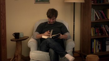 Movie still from “Your Sister's Sister” (2011), directed by Lynn Shelton – A man sitting in a chair reading a book; Medium shot, High angle