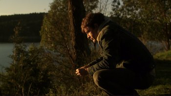 Movie still from “Your Sister's Sister” (2011), directed by Lynn Shelton – A man kneeling down next to a tree in the woods; Wide shot, High angle