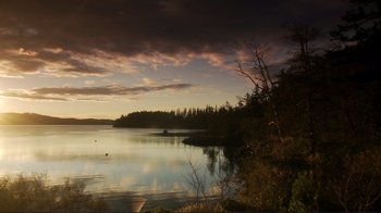 Movie still from “Your Sister's Sister” (2011), directed by Lynn Shelton – A body of water surrounded by trees and a cloudy sky at sunset; Extreme Wide shot, High angle