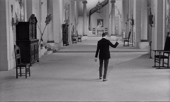 Movie still from “Yoyo” (1965), directed by Pierre Étaix – A man in a suit is walking in a building; Extreme Wide shot, High angle