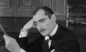 Movie still from “Yoyo” (1965), directed by Pierre Étaix – An old black and white photo of a man in a suit and tie; Close Up shot, High angle