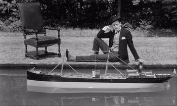 Movie still from “Yoyo” (1965), directed by Pierre Étaix – A black and white photo of a man sitting on a boat; Wide shot, High angle