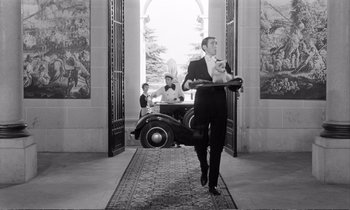 Movie still from “Yoyo” (1965), directed by Pierre Étaix – A black and white photo of a man holding a tray; Wide shot, Low angle