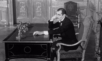 Movie still from “Yoyo” (1965), directed by Pierre Étaix – A black and white photo of a man sitting at a desk; Medium shot, High angle