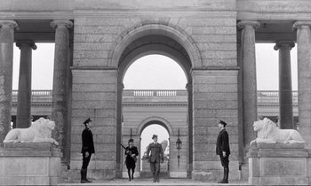 Movie still from “Yoyo” (1965), directed by Pierre Étaix – A black and white photo of a group of men standing in front of an archway; Extreme Wide shot, Low angle