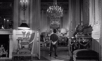 Movie still from “Yoyo” (1965), directed by Pierre Étaix – A person standing in a room with a chandelier; Wide shot, High angle