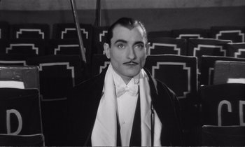 Movie still from “Yoyo” (1965), directed by Pierre Étaix – A black and white photo of a man in a suit and bow tie; Medium shot, High angle