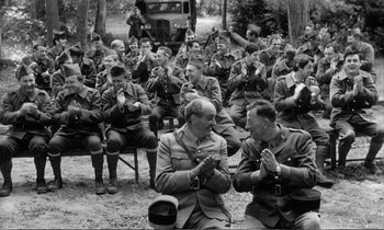 Movie still from “Yoyo” (1965), directed by Pierre Étaix – Black and white photograph of men in military uniforms praying; Medium shot, High angle