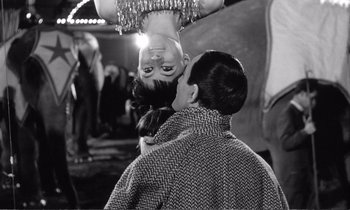 Movie still from “Yoyo” (1965), directed by Pierre Étaix – A man is kissing a woman's face in front of a mannequin head; Medium shot, Over the shoulder angle