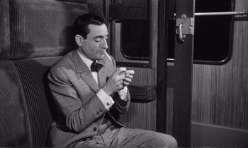 Movie still from “Yoyo” (1965), directed by Pierre Étaix – A black and white photo of a man sitting on a train; Medium shot, High angle