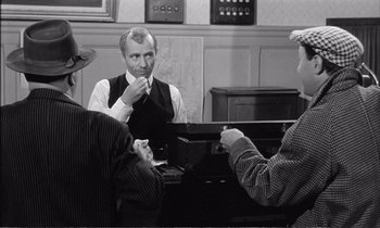 Movie still from “Yoyo” (1965), directed by Pierre Étaix – Three men sitting at a piano in a room; Medium shot, Over the shoulder angle