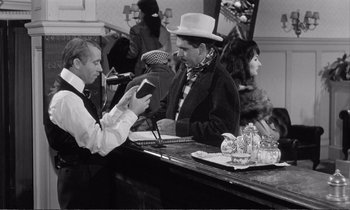 Movie still from “Yoyo” (1965), directed by Pierre Étaix – Two men sitting at a bar talking to each other; Medium shot, Over the shoulder angle