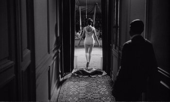 Movie still from “Yoyo” (1965), directed by Pierre Étaix – A woman walking through a doorway in a room; Wide shot, Low angle