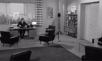 Movie still from “Yoyo” (1965), directed by Pierre Étaix – A man sitting at a desk in a living room; Wide shot, High angle