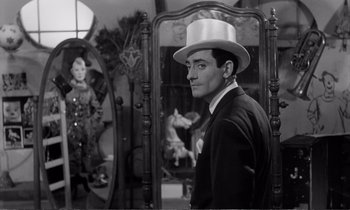 Movie still from “Yoyo” (1965), directed by Pierre Étaix – A black and white photo of a man wearing a white hat; Medium shot, Over the shoulder angle