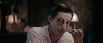 Movie still from “Yves Saint Laurent” (2014), directed by Jalil Lespert – A person wearing glasses and a white shirt; Close Up shot, Over the shoulder angle