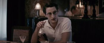 Movie still from “Yves Saint Laurent” (2014), directed by Jalil Lespert – A man sitting at a table with a glass of milk; Close Up shot, Over the shoulder angle