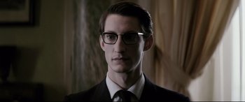 Movie still from “Yves Saint Laurent” (2014), directed by Jalil Lespert – A man in a suit and glasses is looking at the camera; Close Up shot, Low angle