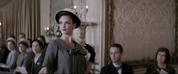Movie still from “Yves Saint Laurent” (2014), directed by Jalil Lespert – A woman in a hat and gloves standing next to a man in a suit and bow tie; Medium shot, Low angle