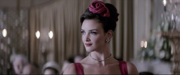 Movie still from “Yves Saint Laurent” (2014), directed by Jalil Lespert – A woman with a rose in her hair and a diamond necklace; Close Up shot, Over the shoulder angle