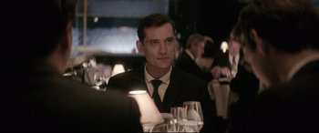 Movie still from “Yves Saint Laurent” (2014), directed by Jalil Lespert – A man sitting at a table with a glass of wine in front of him; Close Up shot, Over the shoulder angle