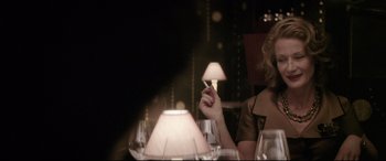 Movie still from “Yves Saint Laurent” (2014), directed by Jalil Lespert – A woman sitting at a dinner table holding a cigarette; Close Up shot, Over the shoulder angle