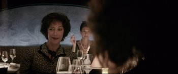 Movie still from “Yves Saint Laurent” (2014), directed by Jalil Lespert – A group of people sitting at a table with wine glasses; Close Up shot, Over the shoulder angle