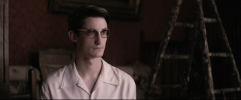 Movie still from “Yves Saint Laurent” (2014), directed by Jalil Lespert – A man wearing glasses and a white shirt; Close Up shot, Low angle
