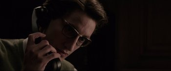 Movie still from “Yves Saint Laurent” (2014), directed by Jalil Lespert – A young man wearing glasses is holding a microphone; Close Up shot, Low angle
