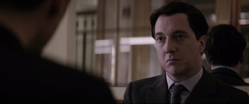 Movie still from “Yves Saint Laurent” (2014), directed by Jalil Lespert – A person wearing a suit and tie; Close Up shot, Over the shoulder angle