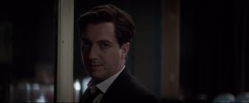 Movie still from “Yves Saint Laurent” (2014), directed by Jalil Lespert – A person wearing a suit and tie; Close Up shot, Over the shoulder angle