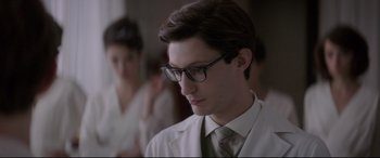 Movie still from “Yves Saint Laurent” (2014), directed by Jalil Lespert – A man wearing glasses and a lab coat; Close Up shot, Over the shoulder angle