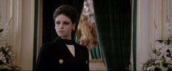 Movie still from “Yves Saint Laurent” (2014), directed by Jalil Lespert – A woman in a black suit standing in front of a green curtain; Close Up shot, Low angle