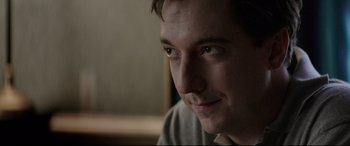 Movie still from “Yves Saint Laurent” (2014), directed by Jalil Lespert – A man's face in a dark room; Close Up shot, Over the shoulder angle