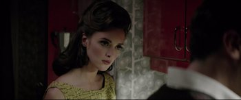 Movie still from “Yves Saint Laurent” (2014), directed by Jalil Lespert – A beautiful young woman with a yellow and black dress; Close Up shot, Over the shoulder angle