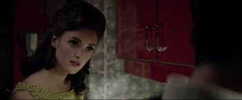 Movie still from “Yves Saint Laurent” (2014), directed by Jalil Lespert – A woman standing next to a red cabinet in a kitchen; Close Up shot, Over the shoulder angle