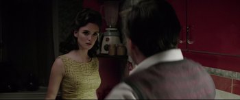 Movie still from “Yves Saint Laurent” (2014), directed by Jalil Lespert – A woman in a yellow dress looking at a man in a white shirt in front of a blender; Medium shot, Over the shoulder angle