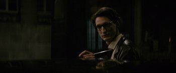 Movie still from “Yves Saint Laurent” (2014), directed by Jalil Lespert – A man in glasses holding a pair of scissors in his hands; Close Up shot, Over the shoulder angle