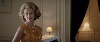 Movie still from “Yves Saint Laurent” (2014), directed by Jalil Lespert – A woman in a yellow dress is holding a computer; Close Up shot, Over the shoulder angle