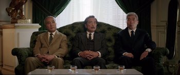 Movie still from “Yves Saint Laurent” (2014), directed by Jalil Lespert – A group of men sitting on a couch in a living room; Medium shot, High angle