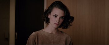 Movie still from “Yves Saint Laurent” (2014), directed by Jalil Lespert – A beautiful young woman with a short brown curly hair; Close Up shot, Over the shoulder angle