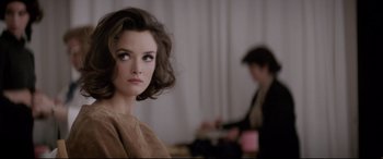 Movie still from “Yves Saint Laurent” (2014), directed by Jalil Lespert – A beautiful woman with short brown hair and brown eyes; Close Up shot, Over the shoulder angle
