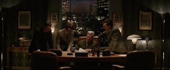 Movie still from “Yves Saint Laurent” (2014), directed by Jalil Lespert – A group of men sitting at a table in front of a window; Medium shot, High angle