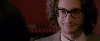 Movie still from “Yves Saint Laurent” (2014), directed by Jalil Lespert – A person wearing glasses and a suit; Close Up shot, Over the shoulder angle