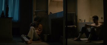 Movie still from “Yves Saint Laurent” (2014), directed by Jalil Lespert – A man sitting on the ground in a room; Wide shot, High angle