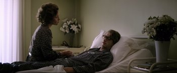 Movie still from “Yves Saint Laurent” (2014), directed by Jalil Lespert – A man is in a hospital bed talking to a woman; Medium shot, High angle