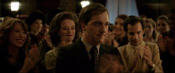 Movie still from “Yves Saint Laurent” (2014), directed by Jalil Lespert – A person wearing a suit and tie; Close Up shot, Over the shoulder angle