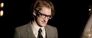 Movie still from “Yves Saint Laurent” (2014), directed by Jalil Lespert – A man in a suit and tie wearing glasses; Close Up shot, Low angle