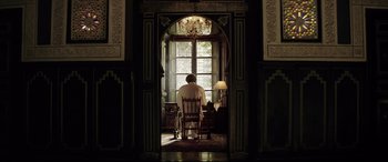 Movie still from “Yves Saint Laurent” (2014), directed by Jalil Lespert – A man sitting in a chair in front of an open window; Wide shot, Low angle